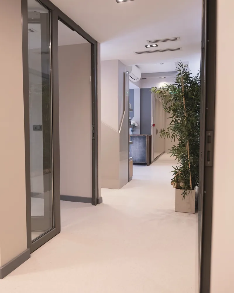Corredor de clínica com porta de vidro e planta
