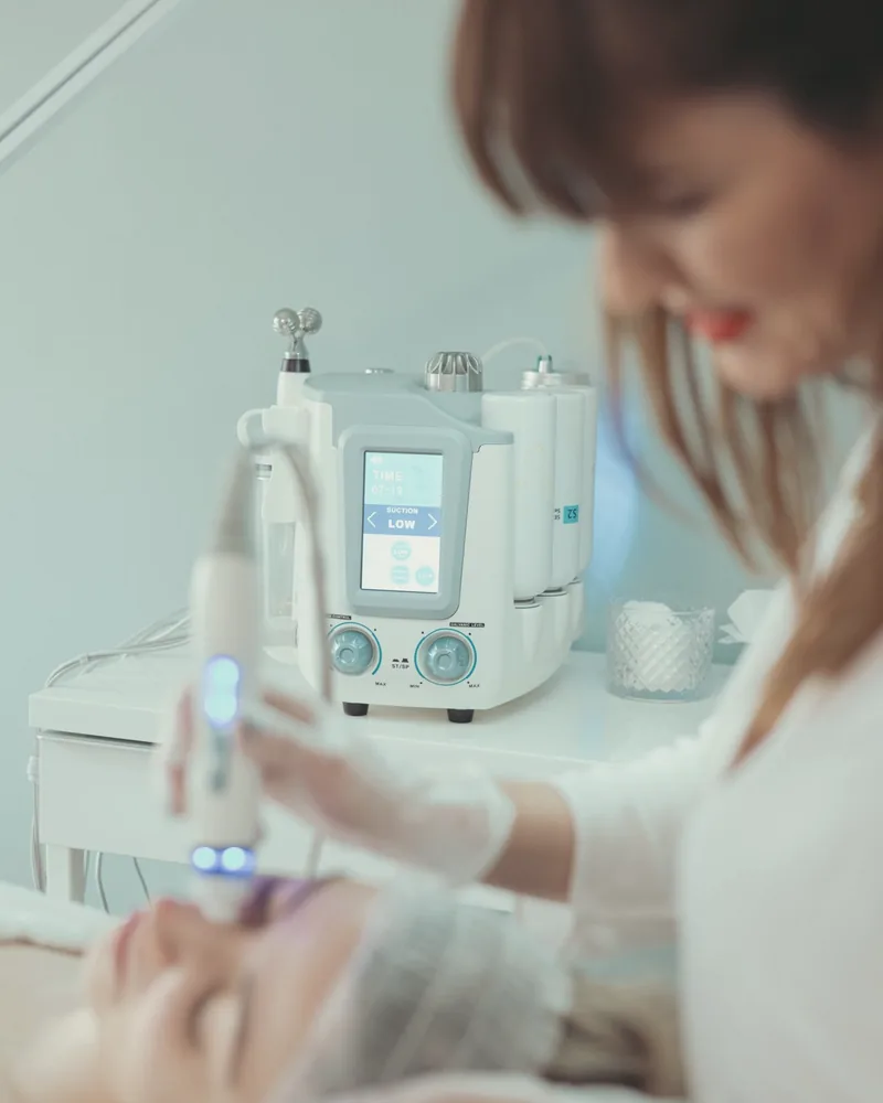 Profissional com aparelho facial em sala clara